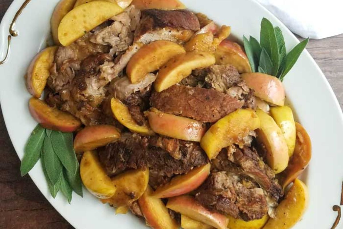 Platter of roasted pork with browned apple slices and sage leaves, served on a white dish—a flavor-packed addition to your dinner routine.