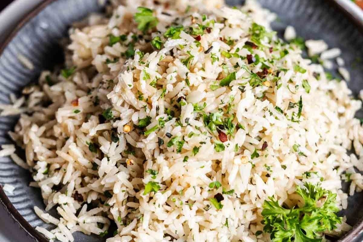 A plate of cooked white rice garnished with chopped parsley and herbs makes for one of the most Simple Rice Recipes, offering a fresh twist on classic Rice Dishes.