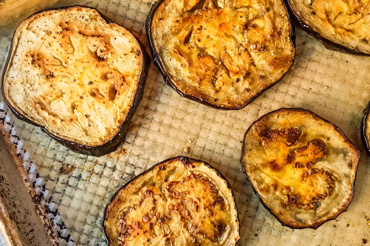 Sliced roasted eggplants on a baking sheet, lightly browned and seasoned, with visible grill marks and a textured background—an irresistible dish inspired by popular recipes that have been saved thousands of times.