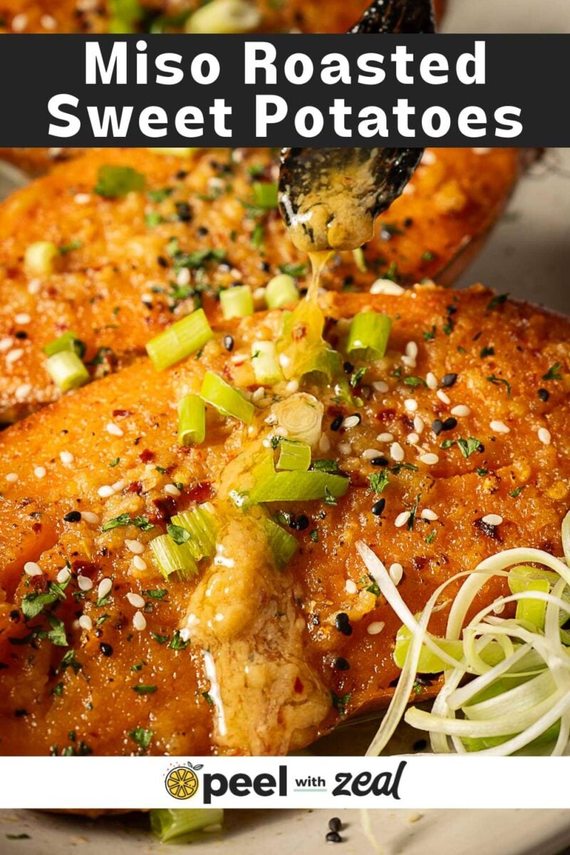 Close-up of Miso Sweet Potatoes roasted to perfection, garnished with chopped green onions and sesame seeds, as a savory sauce is being drizzled on top.