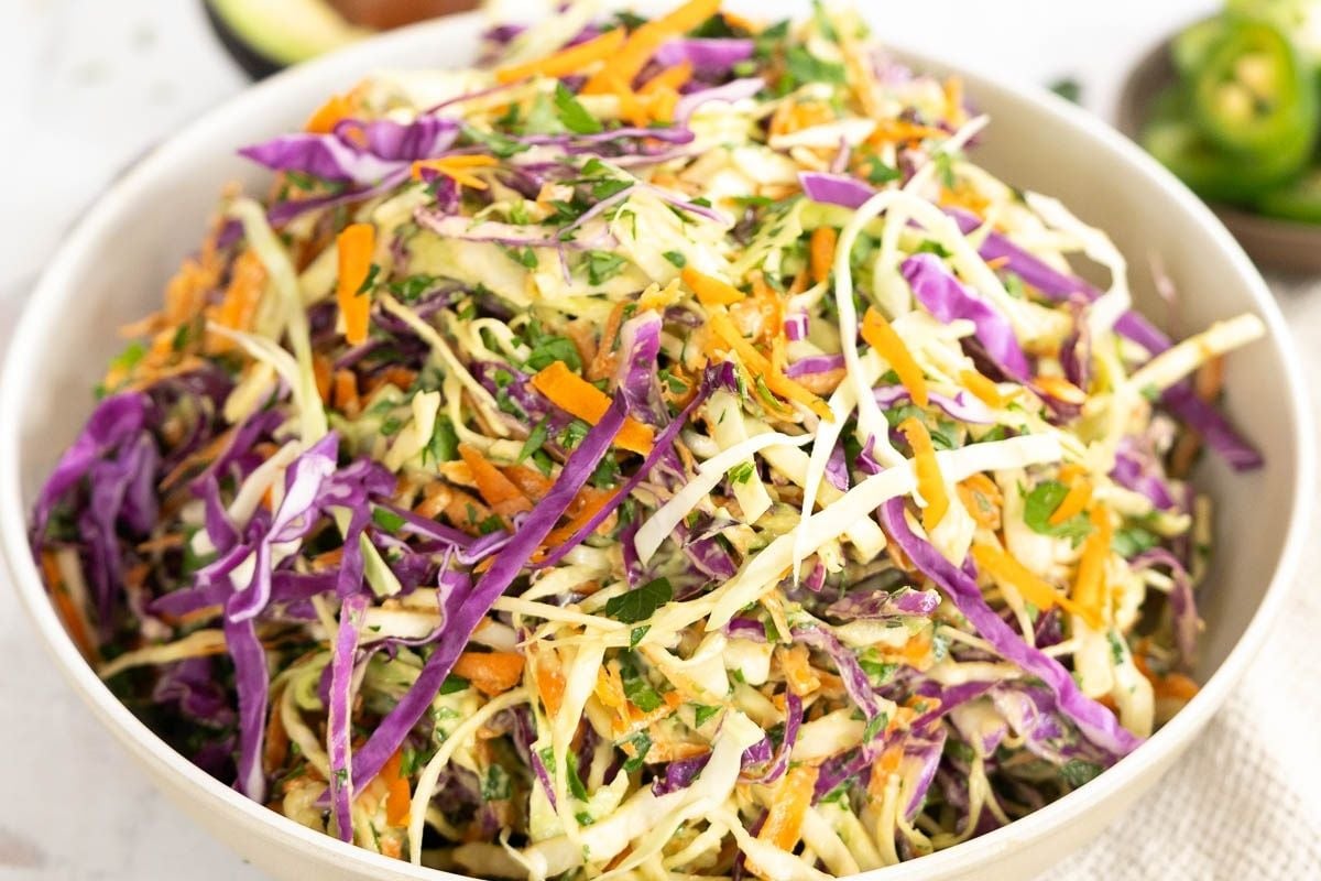 A bowl of coleslaw made with shredded green and purple cabbage, carrots, and herbs, mixed with a creamy dressing—perfect for easy recipes that add a fresh touch to family meals.