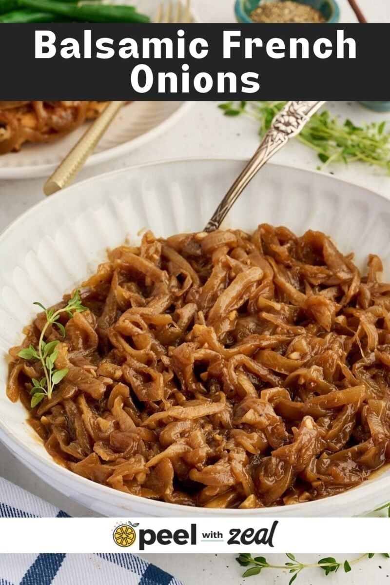 A bowl of caramelized frenched onions topped with a sprig of thyme and a silver spoon.