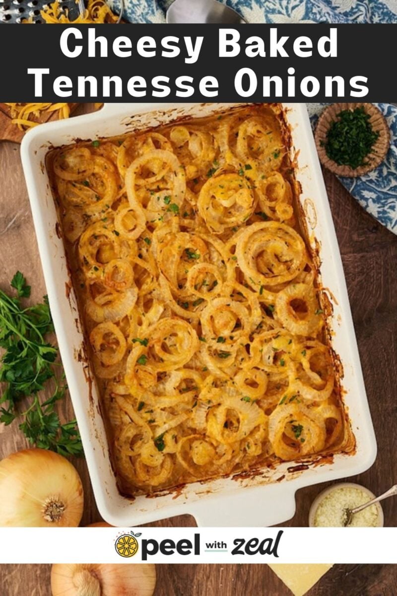 A white rectangular baking dish filled with cheesy Tennessee onions topped with fresh herbs.
