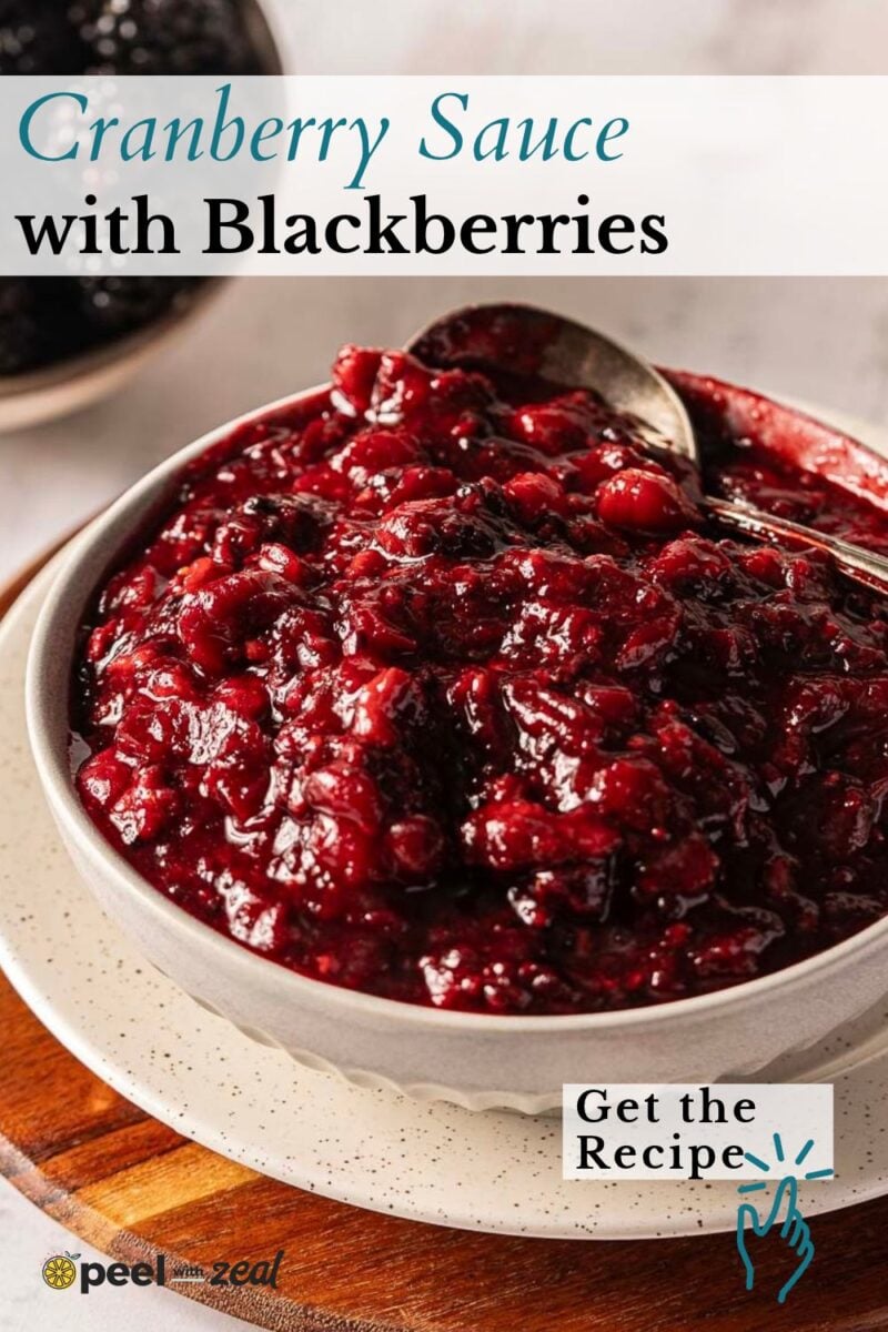 A bowl of cranberry sauce with blackberries and a spoon.