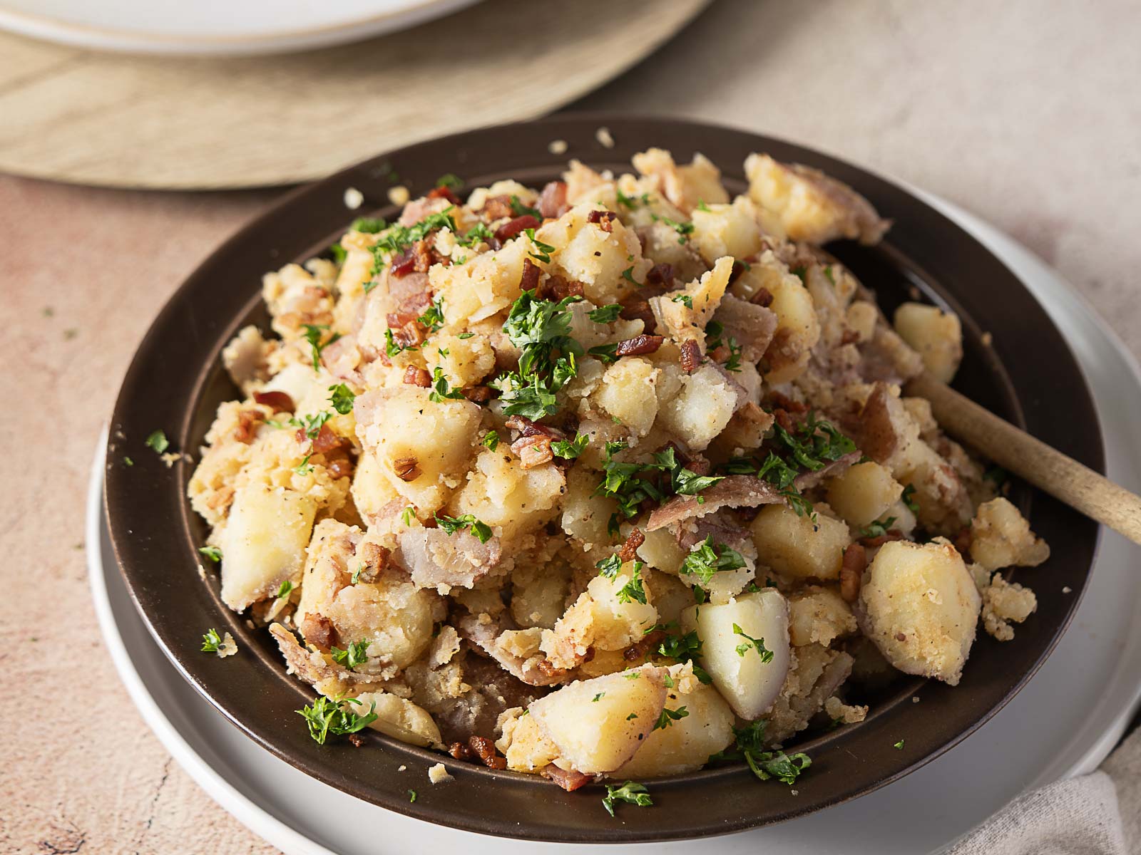 A bowl of potato salad, a classic side dish topped with bacon bits and fresh parsley.