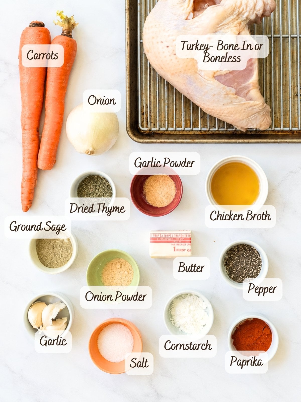 Ingredients for slow cooker turkey breast displayed with labels: carrots, onion, chicken broth, turkey breast on a rack, butter, and bowls of thyme, garlic, sage, onion powder, salt, starch, and spices.